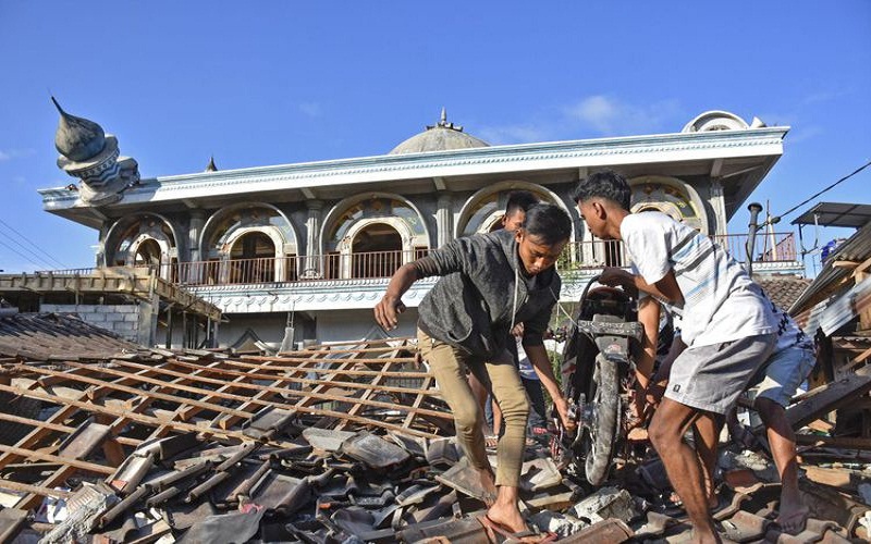 Sejumlah warga mengangkat sepeda motornya dari reruntuhan rumah pascagempa di Desa Wadon, Kecamatan Gunungsari, Lombok Barat, NTB, Senin (6/8/2018). Gempa bumi bermagnitudo 7 mengguncang Lombok, Minggu (5/8/2018) malam. Foto: Antara