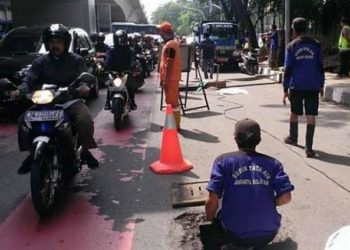 Pasukan oranye dan biru membersihkan gorong-gorong di kawasan Kuningan, Jakarta. Foto: Viva