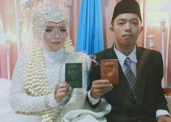 Muhammad Kusmantono (23) dan Niswatun Hasanah (19) melihatkan buku nikah usai menjalankan prosesi akad nikah. Foto: Tribunnews