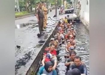 pegawai honorer di Jakarta Barat masuk ke got berisi air keruh dan kotor ketika melakukan tes perpanjangan kontrak. Foto: Suara