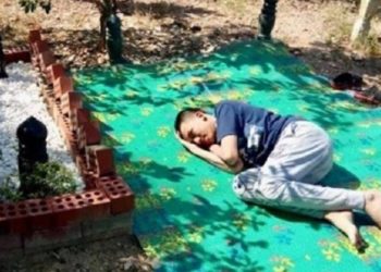 Abang tidur di samping makam ayahnya. Foto: Facebook