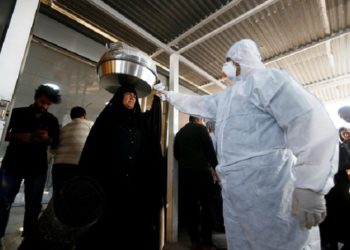 Tim medis memeriksa suhu penumpang di Lintas Perbatasan Shalamcha antara Irak dan Iran. Foto: Reuters