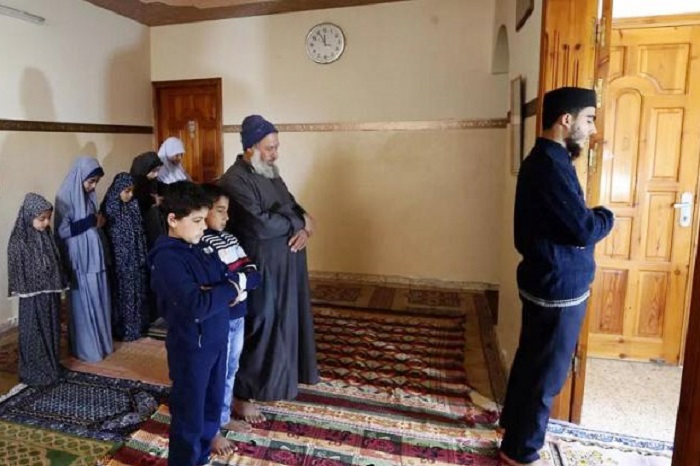 Sebuah keluarga di Gaza shalat Jumat di rumah karena pandemi virus Corona. Foto: Asharq Al-Awsat