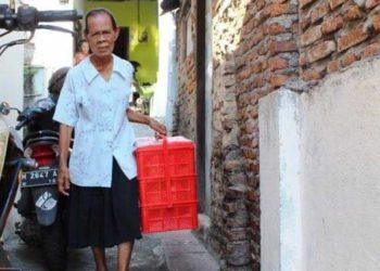 Khotimah (70) atau yang akrab dipanggil Mbah Khotim menenteng keranjang berisi jajanan pasar menyusuri gang-gang sempit di wilayah Jatingaleh Semarang, Jumat (14/8/2020). Foto: Tribunnews